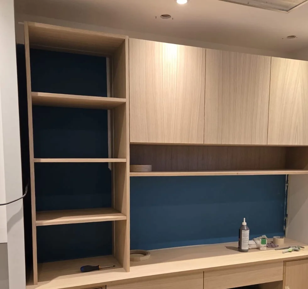 Bureau sur mesure en chêne clair avec plan de travail traversant, rangements hauts et bibliothèque à fond bleu